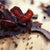 South African biltong slices on a wooden board, showcasing rich, dried meat texture.